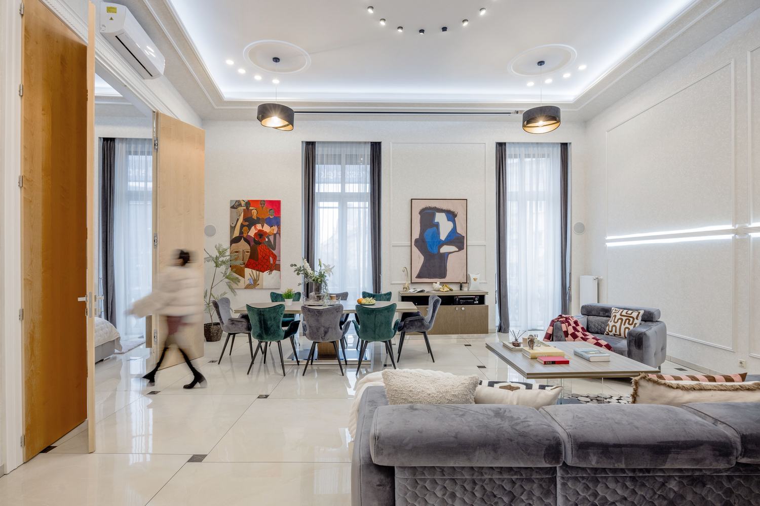 Spacious living and dining room with colorful contemporary art and velvet furniture