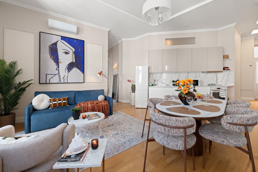 Living and dining space with a blue velvet sofa and round table