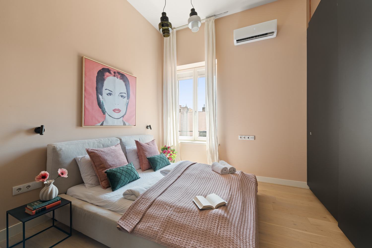 Blush-toned bedroom with pop-art style portrait above the bed